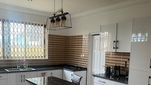 Una cocina moderna con una isla central, armarios blancos y piso de baldosas con diseño.
