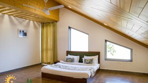 Ein Schlafzimmer mit Holzboden, einem Bett mit weißer Bettwäsche, zwei Fenstern und einem Deckenventilator.