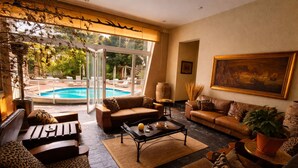 A spacious living area with a pool view, leather sofas, and a coffee table. - Whistletree Luxury Manor (Pretoria)