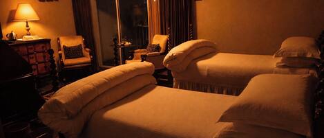 A hotel room with two beds, a lamp, a chair, and a small table.