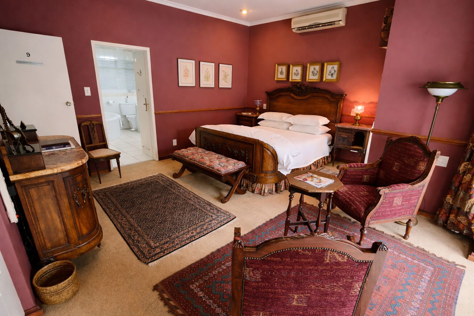 Ein Schlafzimmer mit einem Bett, einem Schreibtisch, einem Stuhl, einer Bank und einem Teppich.