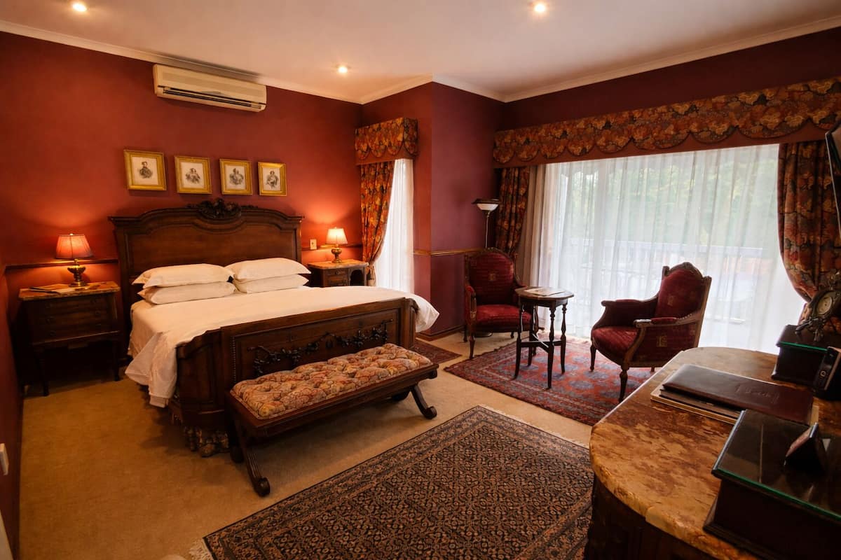 A bedroom with a large bed, a bench, a desk, and a chair.