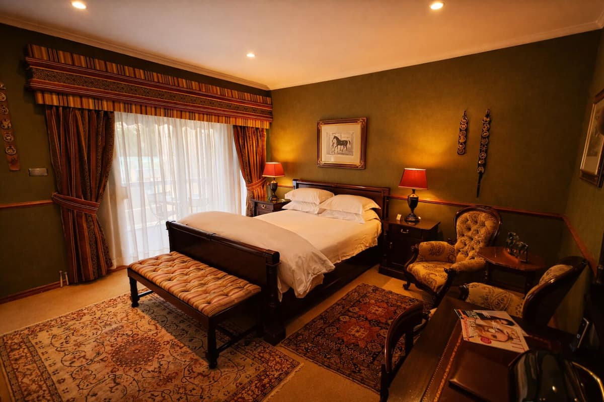 A bedroom with a large bed, two bedside tables with lamps, a chair, and a rug.