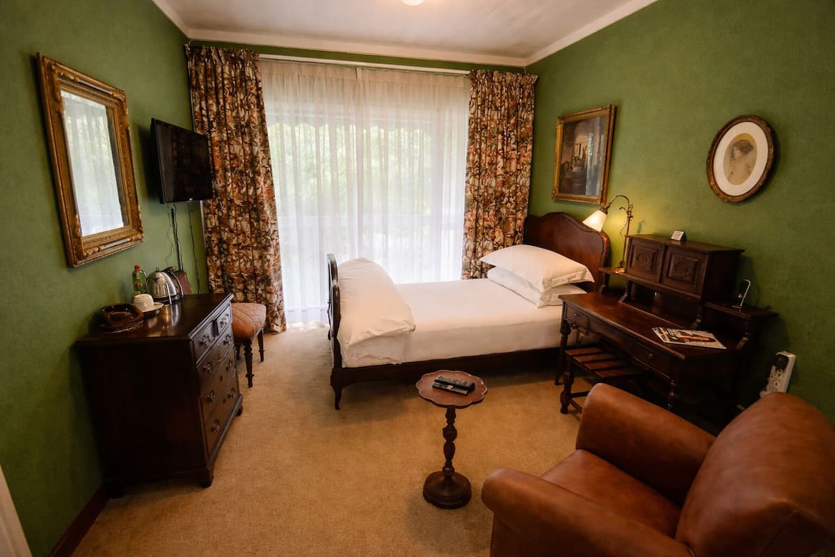 A hotel room with a bed, a desk, a chair, a dresser, a television, and a window with curtains.
