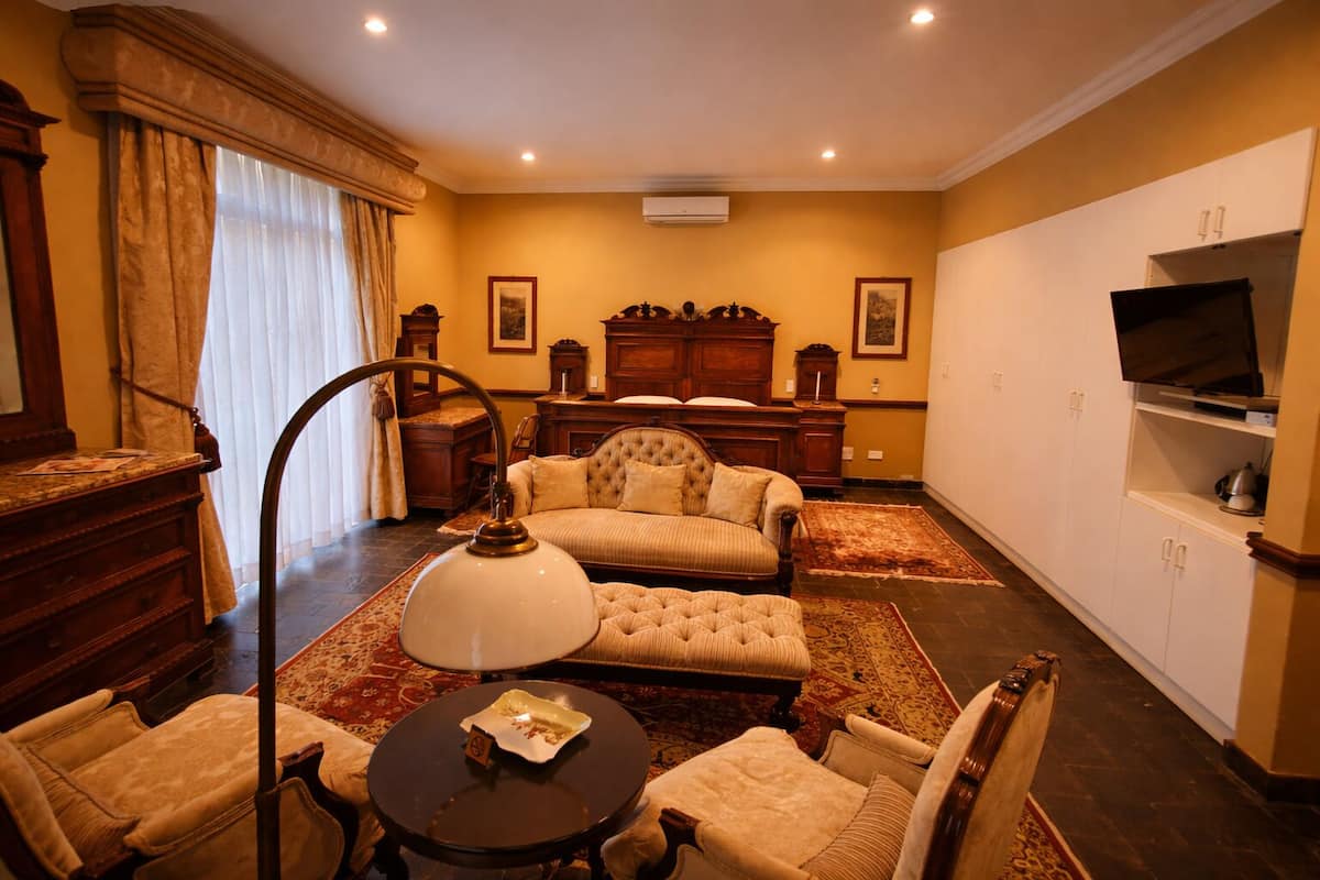 A living room with a sofa, armchairs, a table, a lamp, a TV, and a fireplace.