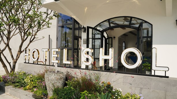 A hotel entrance with a large sign, glass doors, and a well-maintained garden. - Hotel SHOL Ninh Chu (Ninh Chu)