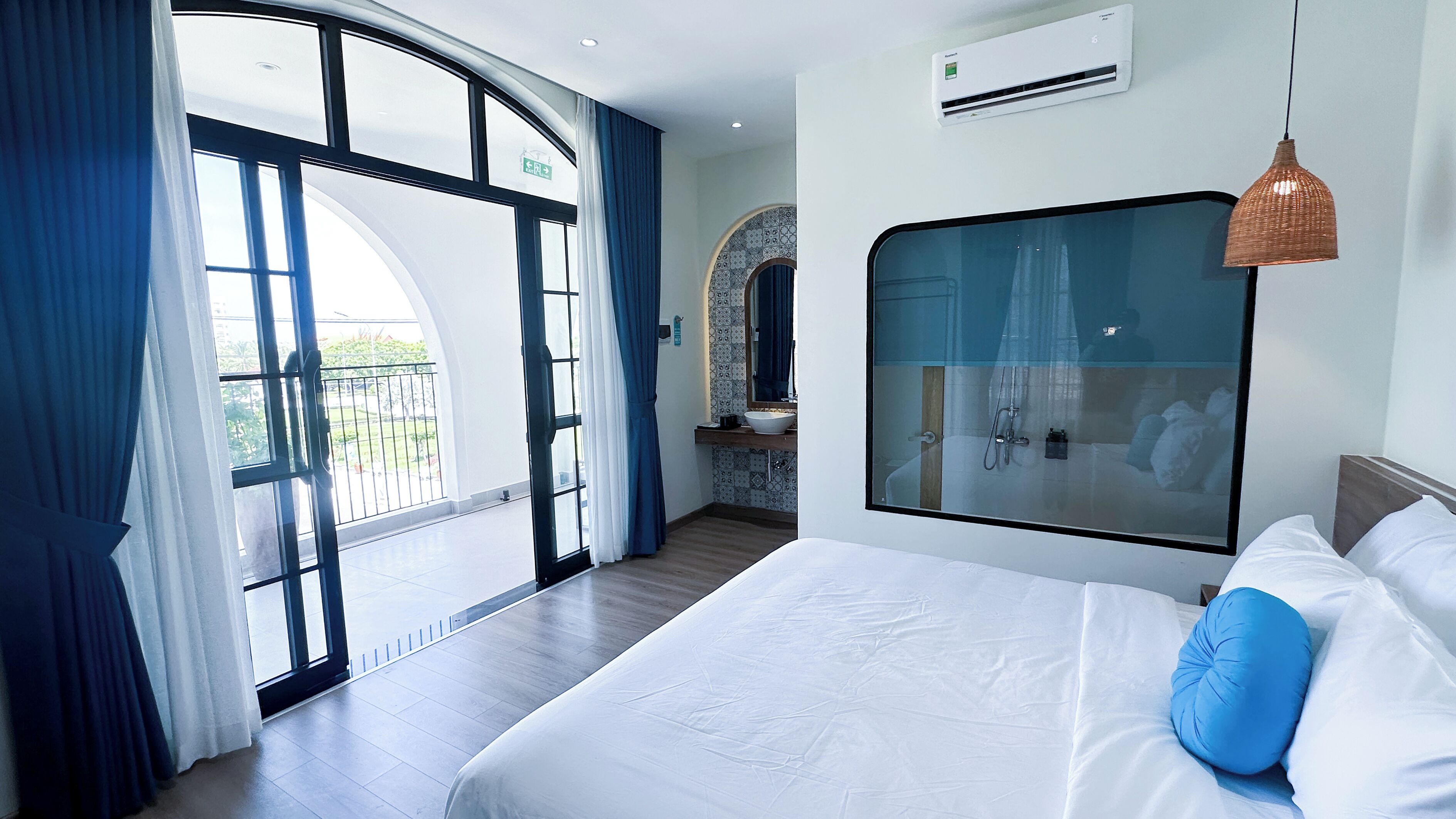A hotel room with a large bed, a bathroom with a shower, and a view of the outdoors.