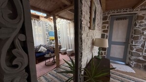 A rustic stone interior with a blue sofa, a small table, and a lamp. - Charming 3-bedroom B&B in serene Manali perfect for getaway (Naggar)