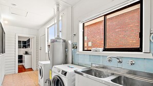 Een wasserette met een wasmachine, droger en een grote boiler.