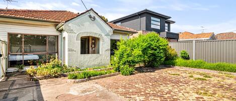 A residential property with a paved driveway, a small garden, and a detached garage.