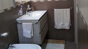 Ein Badezimmer mit Waschbecken, Spiegel, Handtuchhalter und Bidet.
