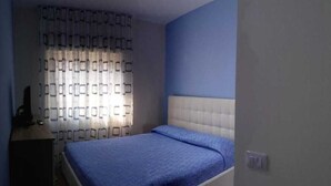 Ein Schlafzimmer mit einem Bett, einem Schminktisch und einem Vorhang.