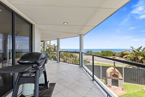 Een balkon met een grill, barbecue en pizzaoven, met uitzicht op de kust.
