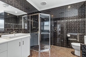 Een moderne badkamer met een douchecabine van glas, een wit wastafelmeubel en een toilet.