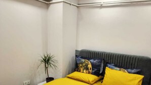 Une chambre à coucher moderne avec un grand lit, une tête de lit ornée d’un motif représentant la lune et un arbre, et une plante en pot.