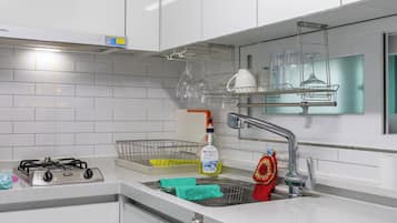 Una cucina moderna con mobili bianchi, piano cottura a gas in acciaio inossidabile, microonde e scolapiatti.