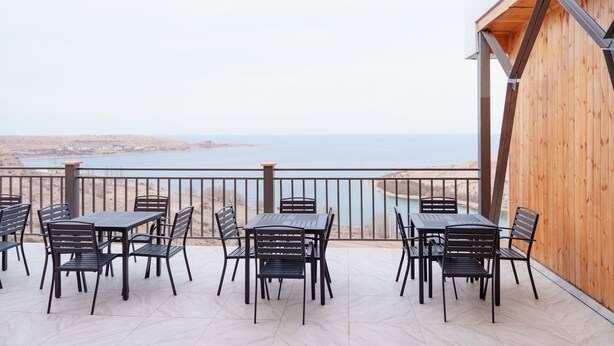 Una terraza con mesa y sillas, con vista a un cuerpo de agua.