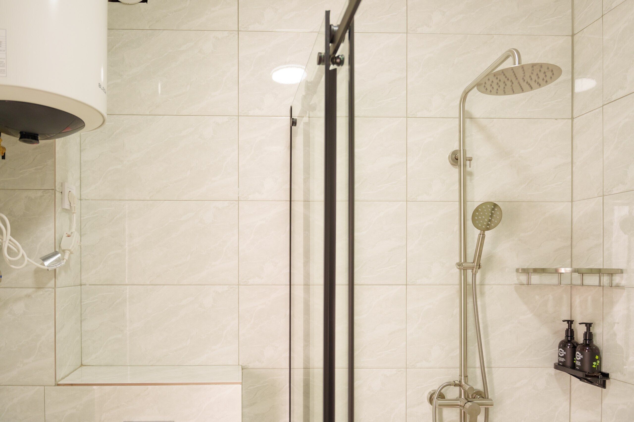 Un baño moderno con cabina de ducha de vidrio, ducha de mano y grifo empotrado.