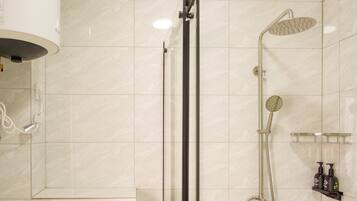 Un baño moderno con cabina de ducha de vidrio, ducha de mano y grifo empotrado.