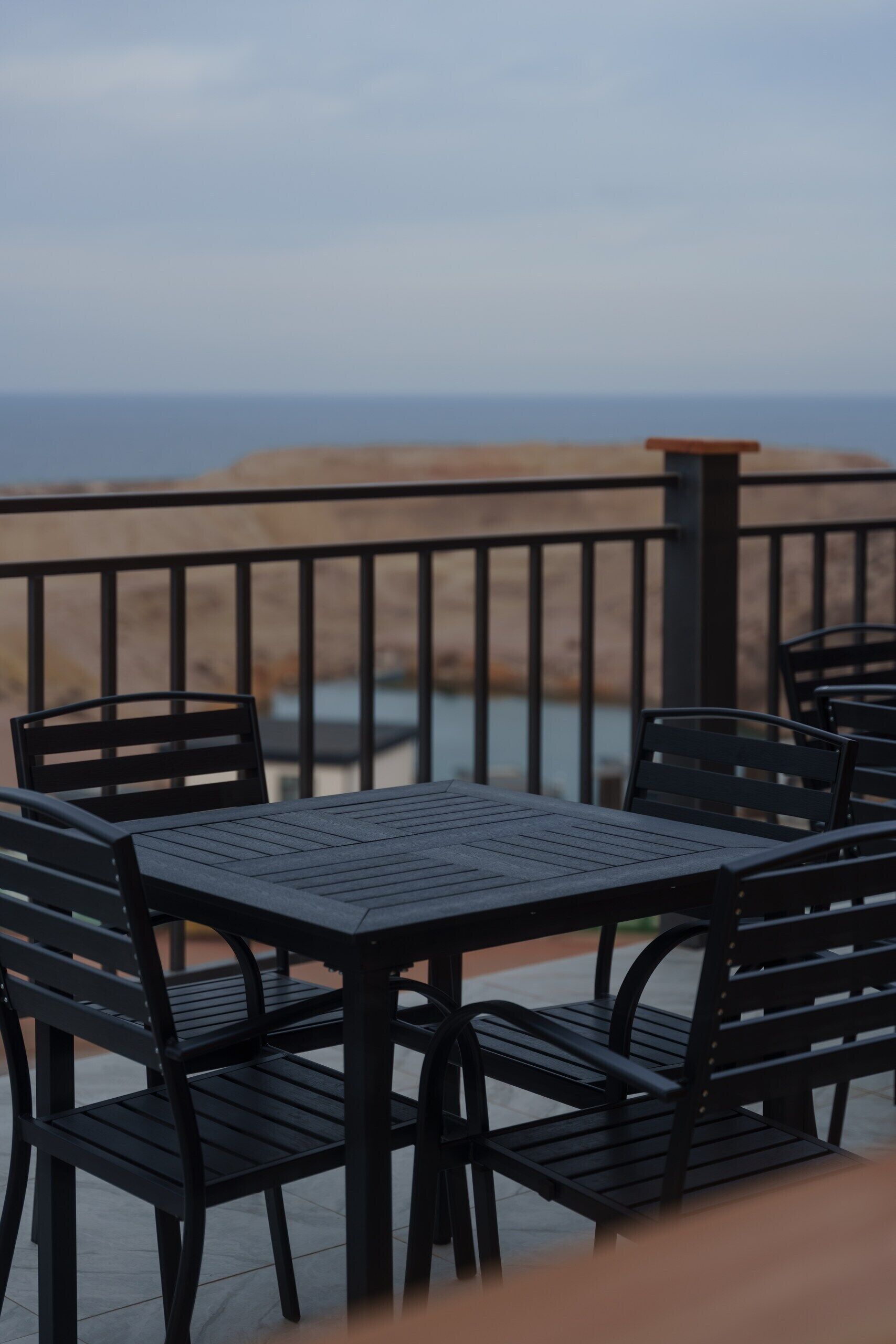 Terraço com mesas e cadeiras, com vista para a praia e o mar.