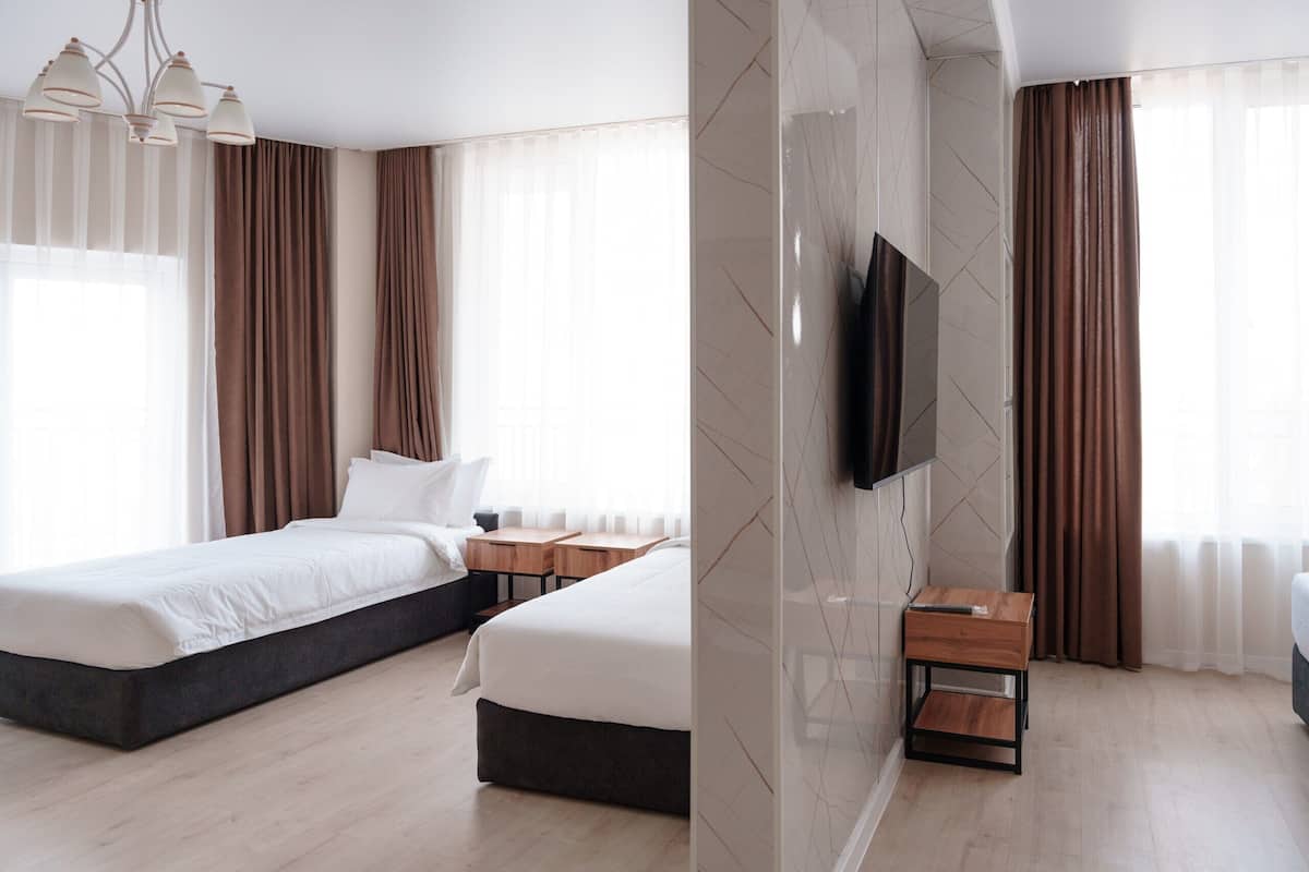 A modern hotel room with a large bed, a TV mounted on the wall, and a small wooden side table.