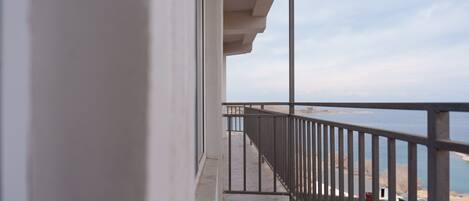 A balcony with a metal railing overlooking a beach.