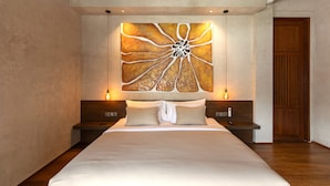 A large bed with a neutral-colored headboard and footboard, flanked by two bedside tables with lamps. A large abstract painting is centered above the bed. - Villa Nordoy 2 by Alfred in Bali (Tabanan)