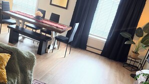 En stue med spisebord, sofa, sofabord med et stearinlys og en potteplante.
