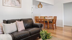 Ein modernes Wohnzimmer mit einer braunen Ledersofa, einem Holzesstisch und Stühlen.