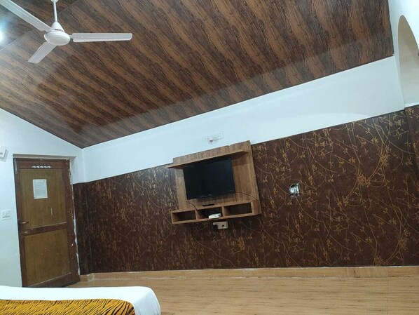 Une pièce avec un plafond en bois, un téléviseur fixé au mur et une porte en bois.