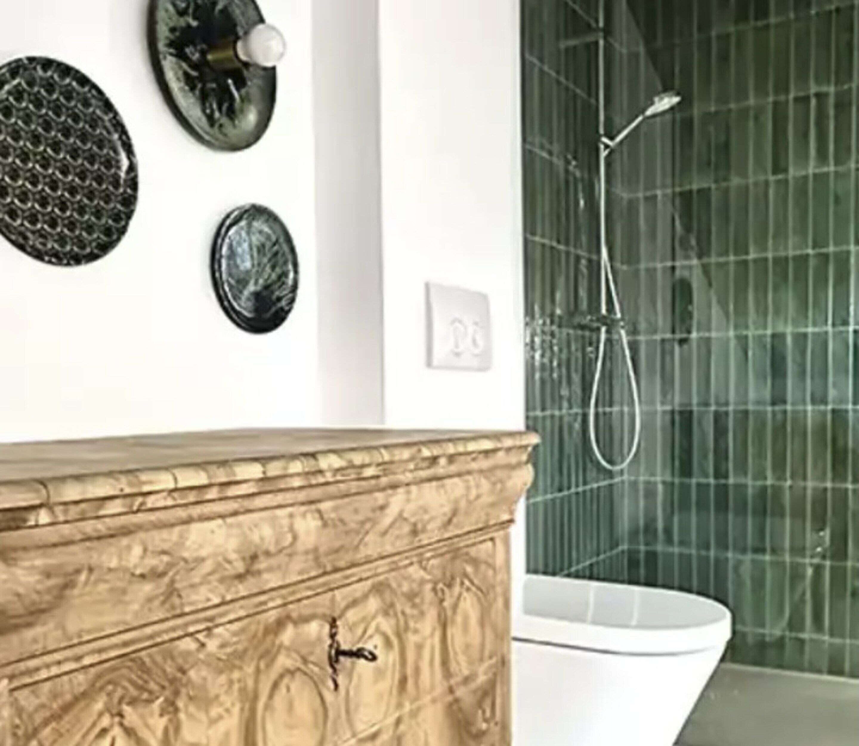 Et badeværelse med kommode i marmor, et hvidt toilet og en glasbrusekabine.