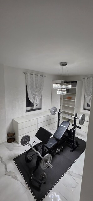 Un gimnasio con barra de press de banca, jaula para sentadillas y discos de pesas.