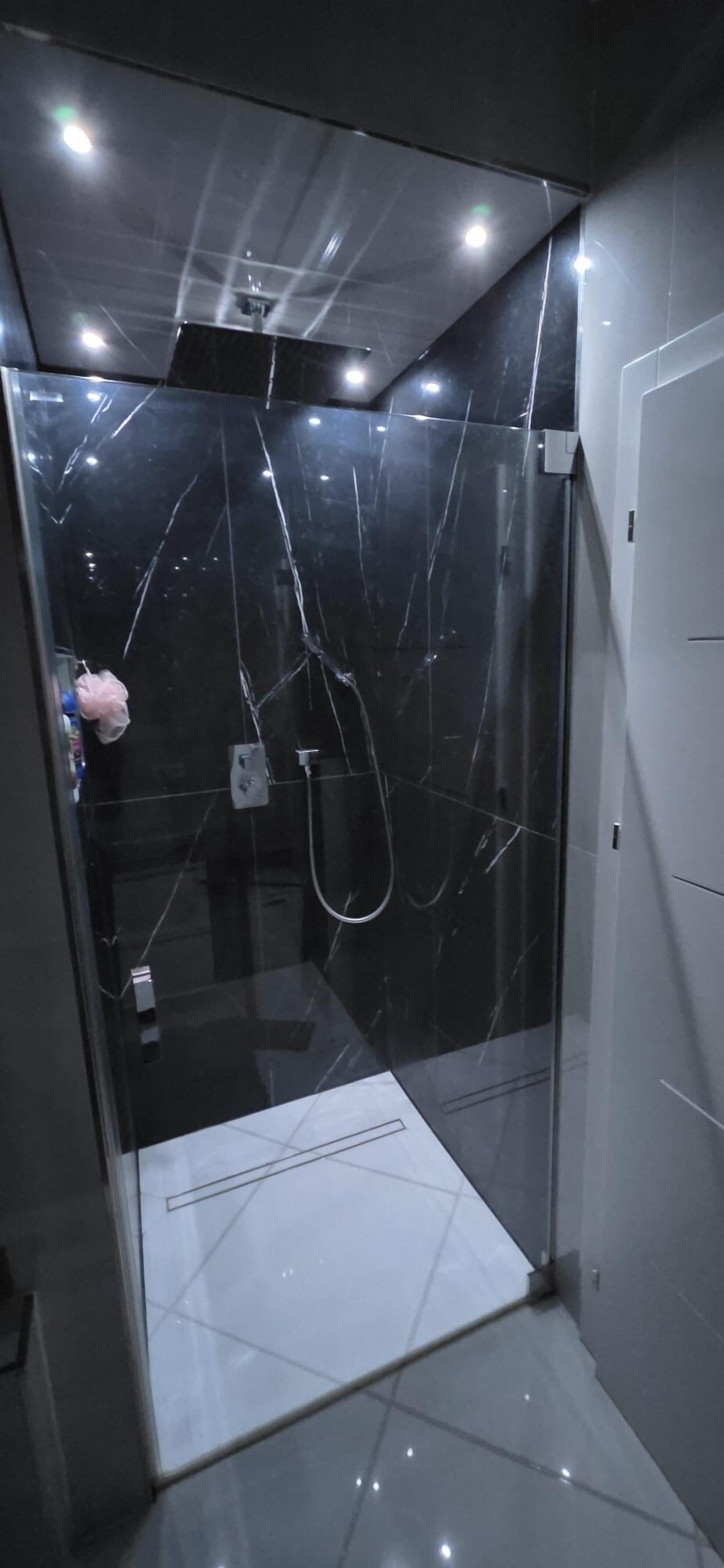 A modern bathroom with a glass enclosure, a shower, and a white tiled floor.