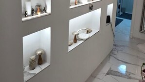 Een hal met gewelfde nissen, decoratieve objecten, een marmeren vloer en een moderne lamp.