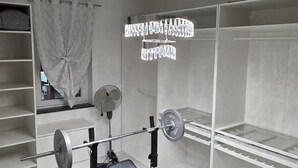 Een sportschool met een bankdrukapparaat, een rek voor squats en losse gewichten.