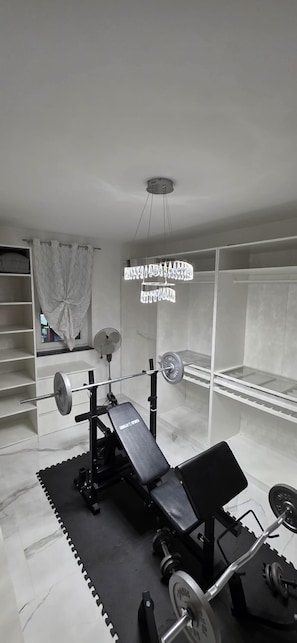 Ein Fitnessraum mit Langhantelbank, Squat-Gestell und Kurzhanteln.