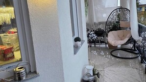 Een overdekt buitengebied met een zithoek, een tafeltje en een decoratief vloerkleed.