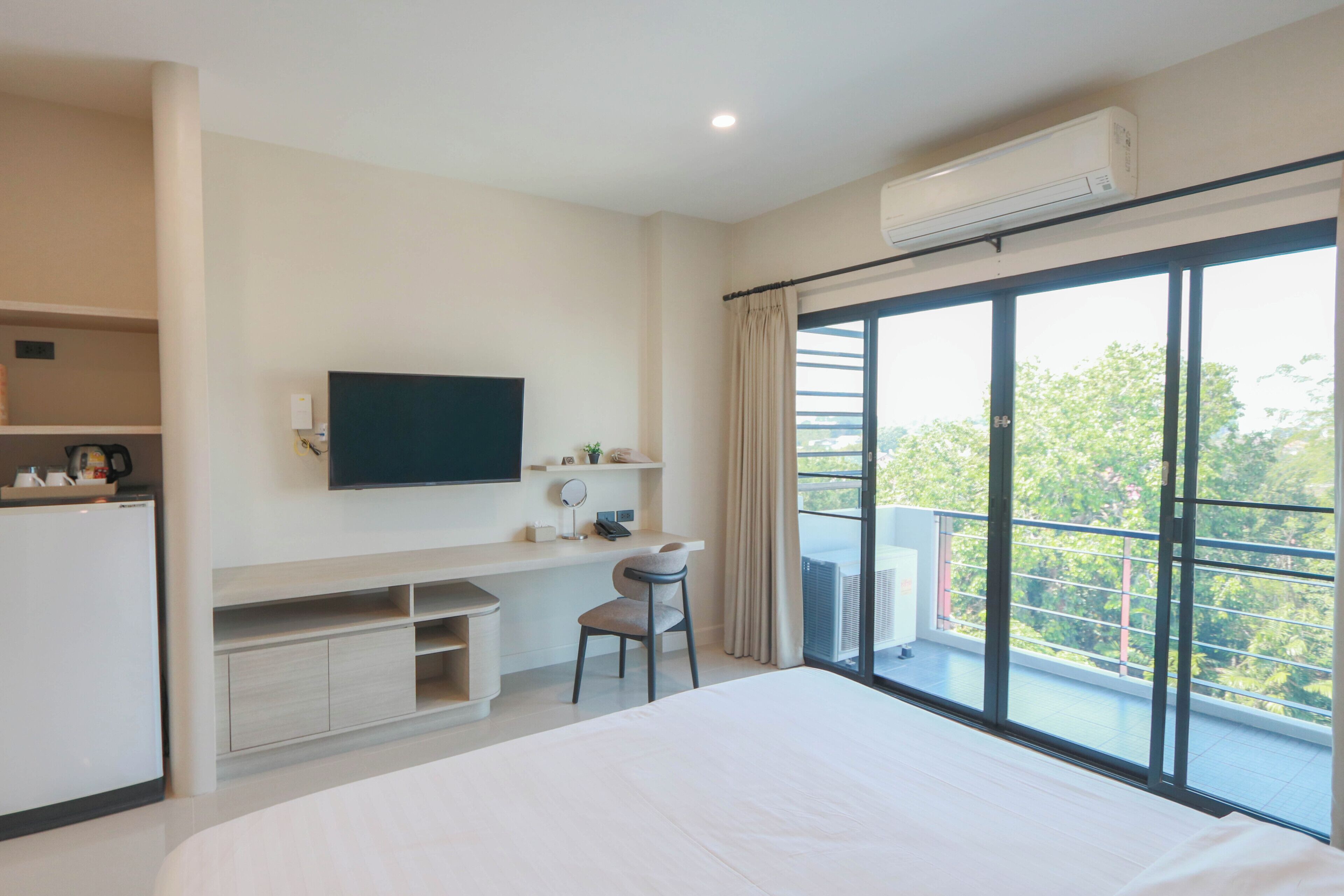 Een moderne hotelkamer met een groot bed, een aan de muur bevestigde televisie, een bureau met stoel en een balkon met uitzicht.