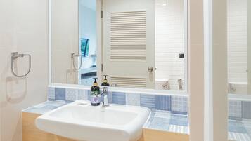 Un baño con un lavamanos blanco, un espejo y una zona de ducha.