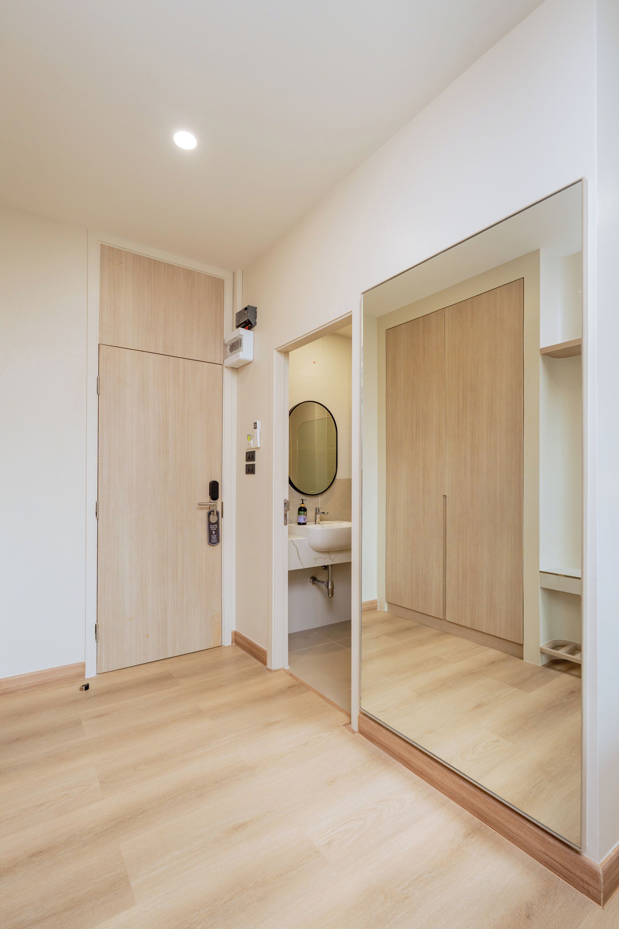 Una habitación moderna y luminosa con piso de madera, un espejo grande y un armario empotrado.