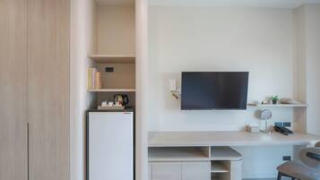 Una habitación moderna con televisión de pantalla plana, escritorio, silla y estanterías integradas.