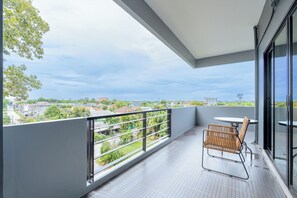 A balcony with a view of a residential area, a table, and a chair.