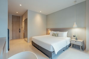 A modern hotel room with a large bed, bedside tables, a mirror, and a bathroom with a bathtub.