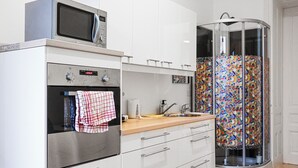 Een keuken met een magnetron, oven en een douchecabine van glas.