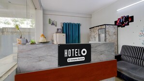 Un espace d’accueil d’hôtel comprenant un comptoir en marbre, un bureau d’accueil, un canapé et un mur orné d’œuvres d’art.