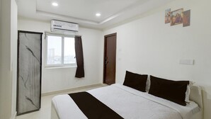 Une chambre à coucher comprenant un lit, un appareil de climatisation, une fenêtre avec des rideaux et une porte.