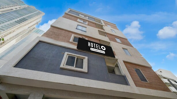 Un bâtiment d’hôtel avec une enseigne indiquant « HOTELO » et le logo de l’entreprise qui gère l’établissement.