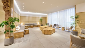 Un intérieur moderne avec un canapé d’angle, une table basse en bois et des plantes en pot.