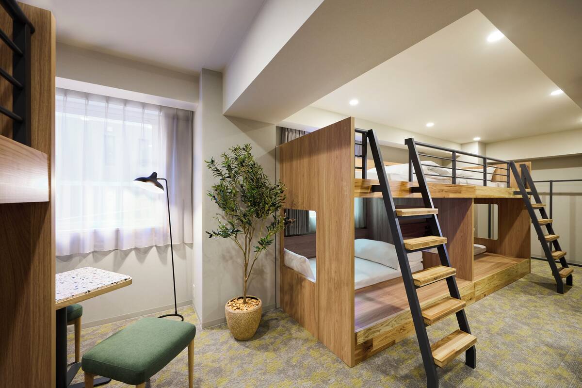 Habitación con literas, un escritorio y una planta en maceta.