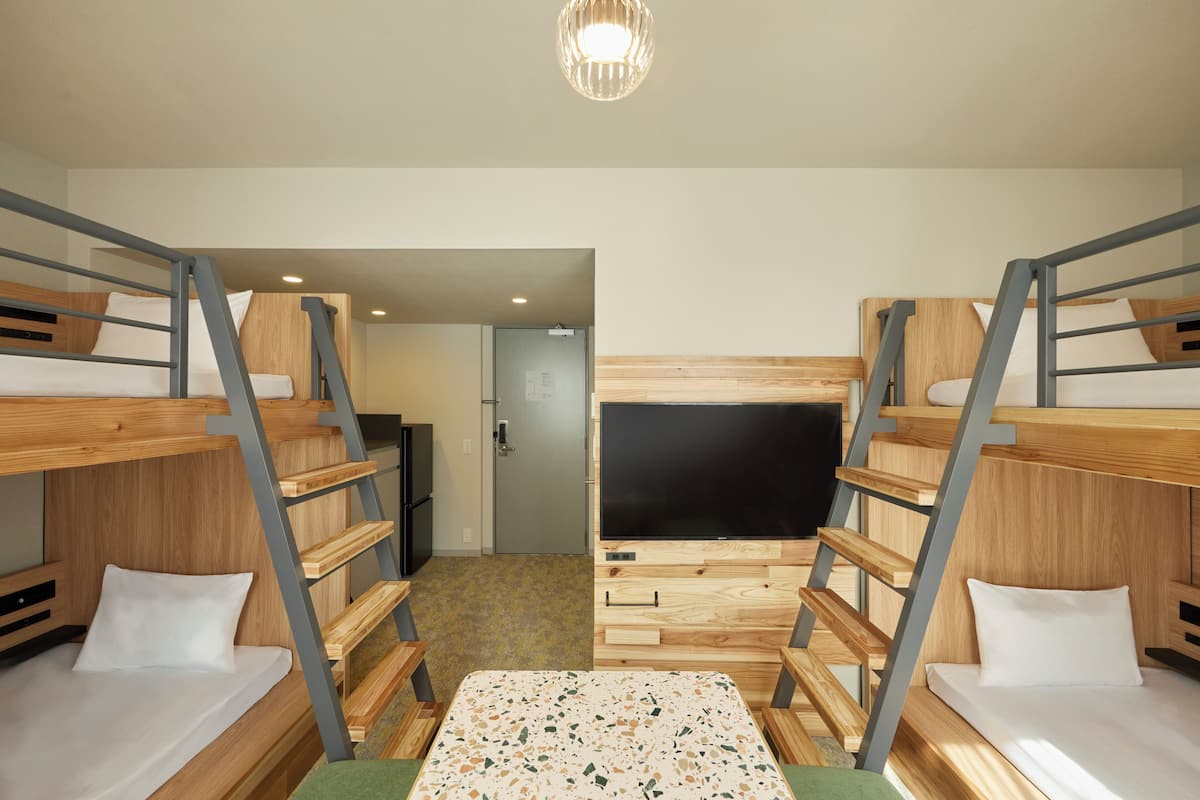 Dormitorio con literas, televisión, muebles de madera y una puerta que da a otra habitación.